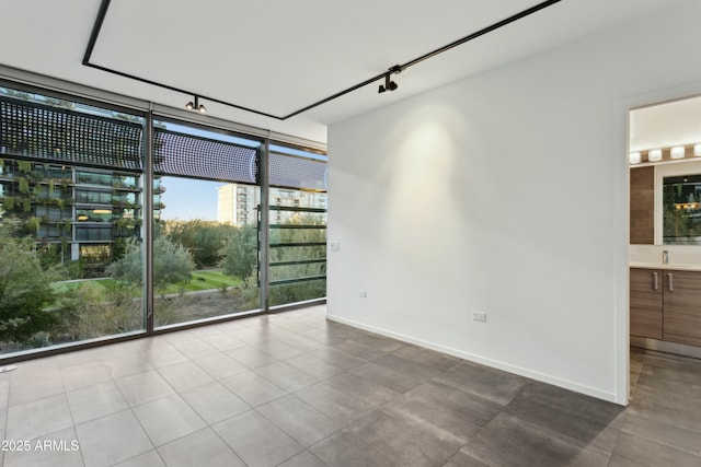 unfurnished room featuring expansive windows and rail lighting