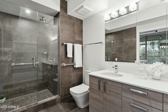 bathroom with tile patterned floors, toilet, an enclosed shower, tile walls, and vanity