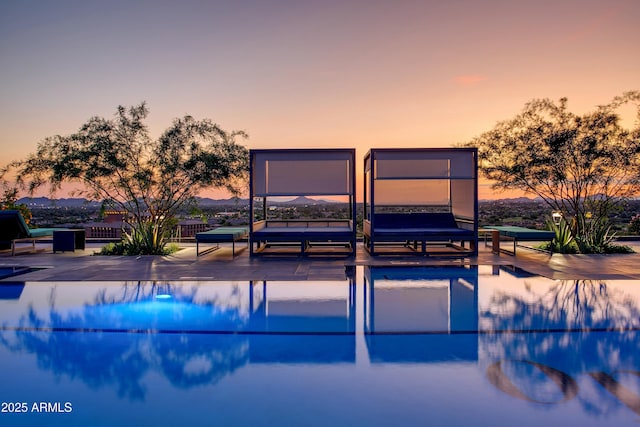 pool at dusk featuring a patio