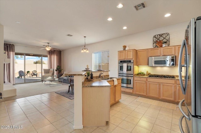 kitchen with ceiling fan with notable chandelier, hanging light fixtures, light brown cabinets, and stainless steel appliances