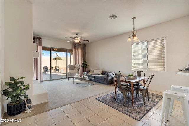 carpeted dining space with ceiling fan with notable chandelier