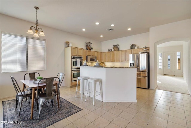 kitchen with light tile patterned floors, appliances with stainless steel finishes, a notable chandelier, and a kitchen island