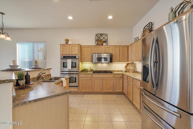 kitchen with light brown cabinets, stainless steel appliances, an inviting chandelier, sink, and hanging light fixtures