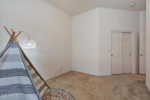 unfurnished bedroom with light colored carpet, a closet, and lofted ceiling