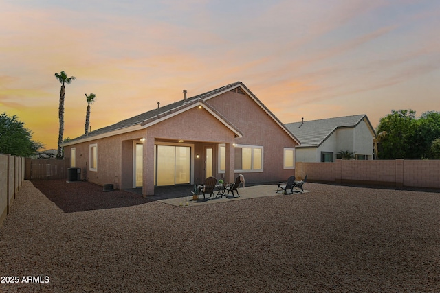 back house at dusk with central AC and a patio