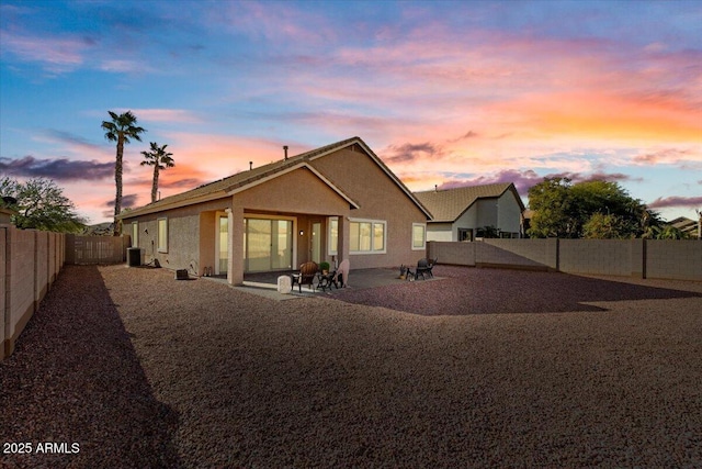 back house at dusk featuring a patio area and central AC unit