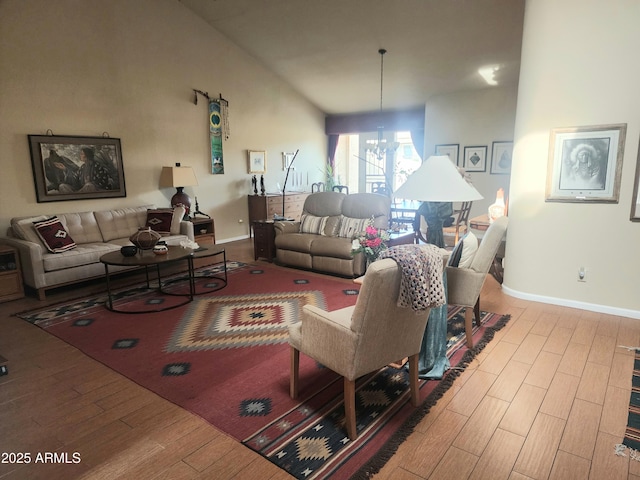 living room with high vaulted ceiling, a chandelier, and light hardwood / wood-style floors