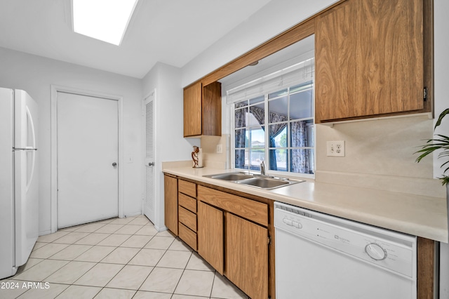 kitchen featuring light tile patterned floors, white appliances, and sink