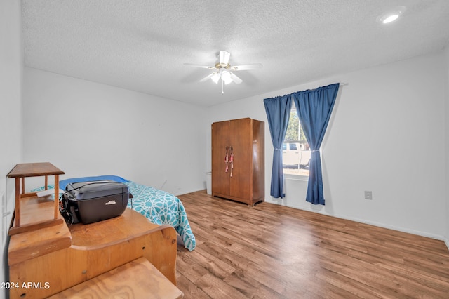 bedroom featuring ceiling fan, a textured ceiling, and wood-type flooring