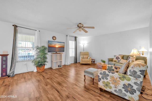 living room with a textured ceiling, ceiling fan, and light hardwood / wood-style flooring