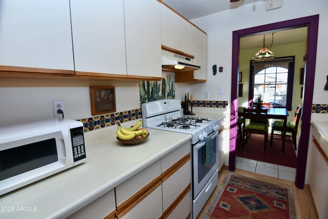 kitchen featuring white cabinetry, white appliances, light tile patterned floors, and pendant lighting