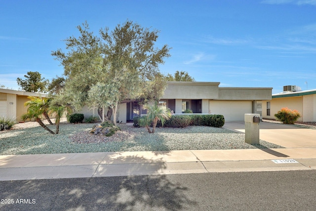 view of front facade with a garage, driveway, and stucco siding