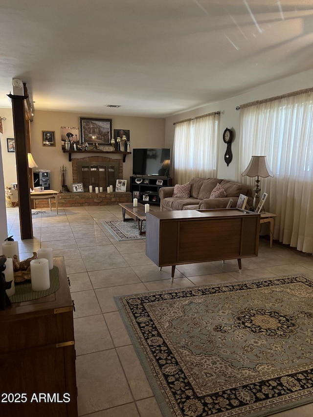 tiled living room featuring a brick fireplace and a healthy amount of sunlight