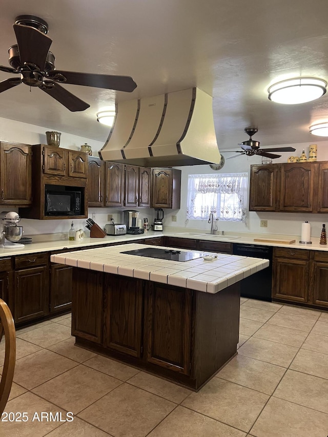 kitchen with a kitchen island, tile countertops, black appliances, and dark brown cabinets