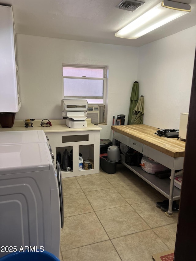 laundry room featuring cooling unit, light tile patterned flooring, and cabinets