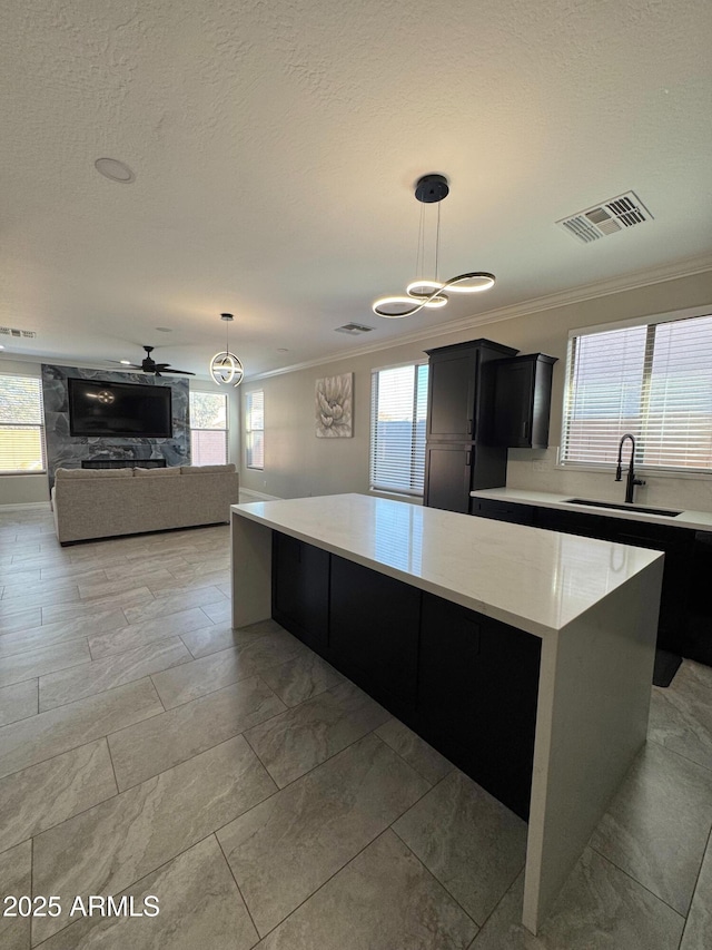 kitchen featuring hanging light fixtures, sink, a kitchen island, and ornamental molding