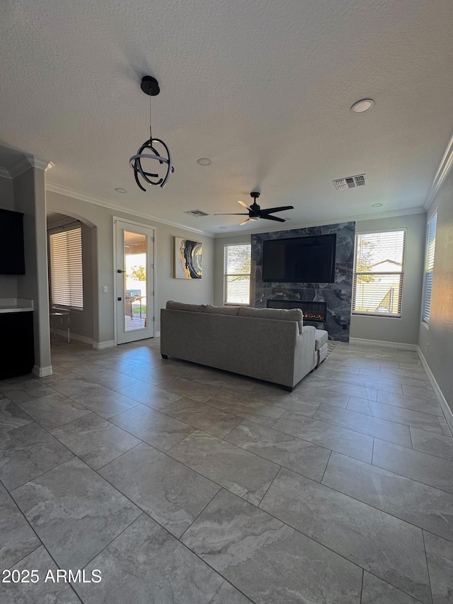 unfurnished living room featuring a fireplace, crown molding, a textured ceiling, and plenty of natural light