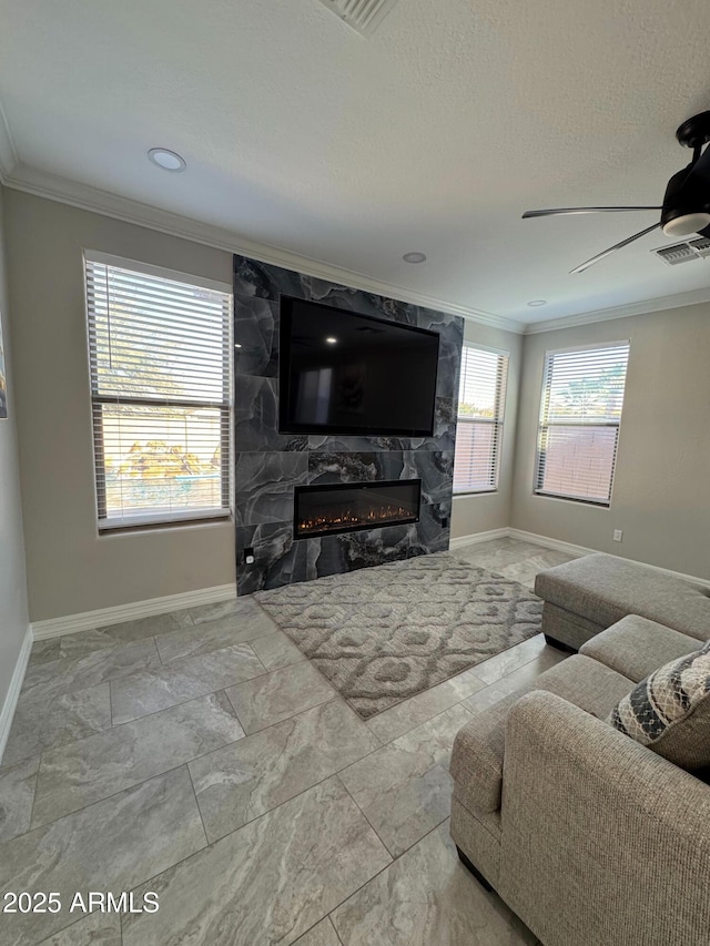 living room with ceiling fan, ornamental molding, a high end fireplace, and a textured ceiling