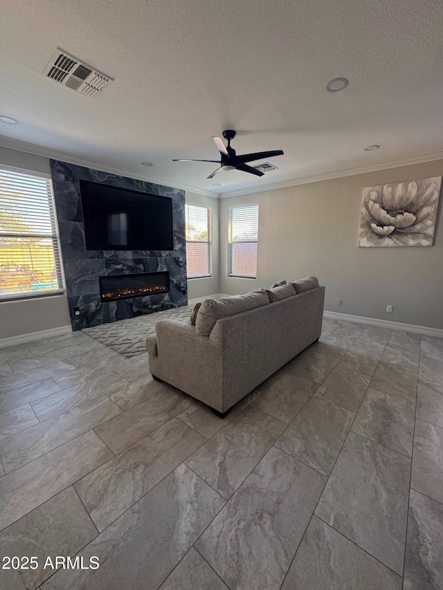 living room with a textured ceiling, crown molding, ceiling fan, and a premium fireplace