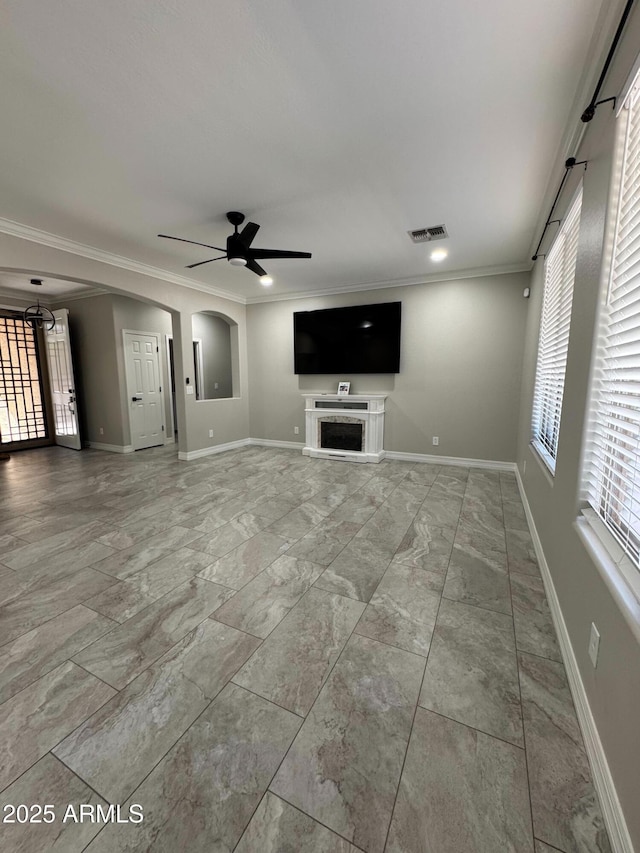 unfurnished living room featuring ceiling fan and ornamental molding