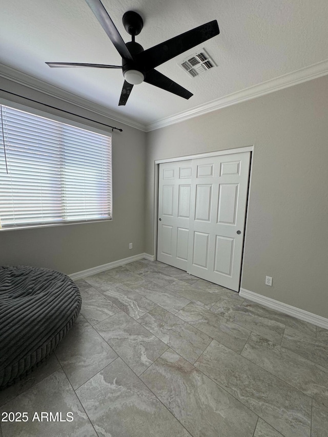 unfurnished bedroom featuring ceiling fan, crown molding, a textured ceiling, and a closet