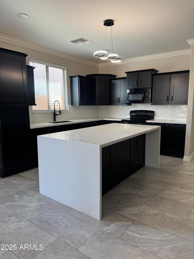 kitchen with sink, pendant lighting, a kitchen island, crown molding, and black appliances