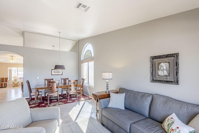 tiled living room with ceiling fan and vaulted ceiling