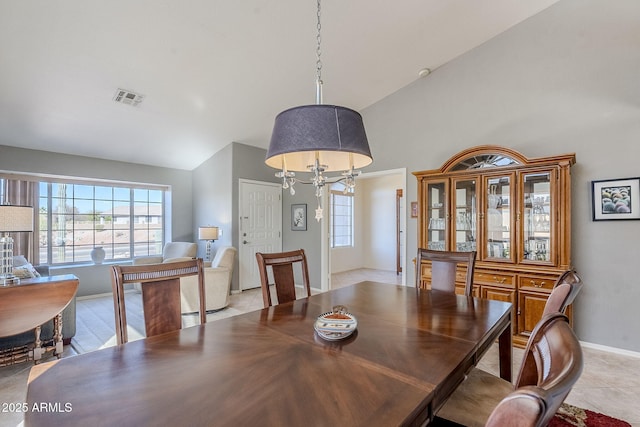 tiled dining room featuring high vaulted ceiling and a chandelier