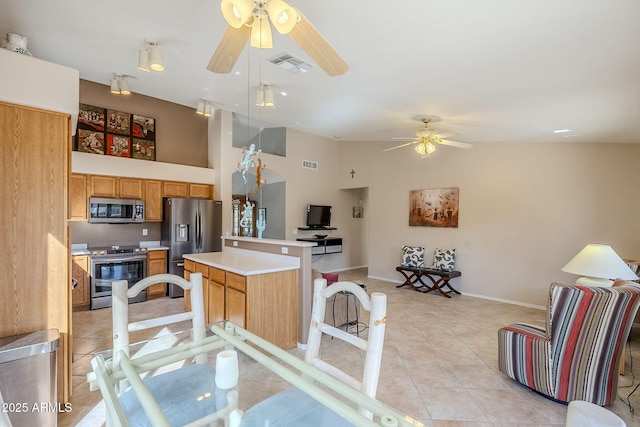 kitchen featuring stainless steel appliances, light tile patterned floors, high vaulted ceiling, a kitchen island, and decorative light fixtures