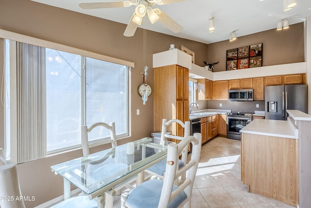 kitchen featuring stainless steel appliances, sink, ceiling fan, light tile patterned floors, and a high ceiling