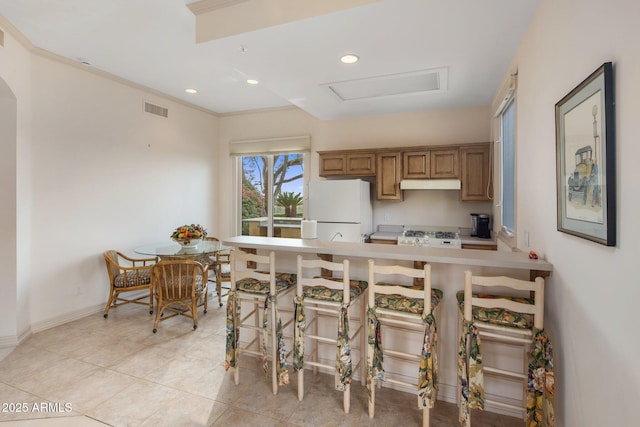 9451 E Happy Valley Rd, Scottsdale, AZ 85255 - kitchen featuring a breakfast bar, white appliances, light countertops, under cabinet range hood, and visible vents