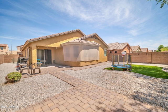 16887 W Belleview St, Goodyear, AZ 85338 - rear view of property featuring a trampoline, a patio area, a fenced backyard, stucco siding, and a tiled roof