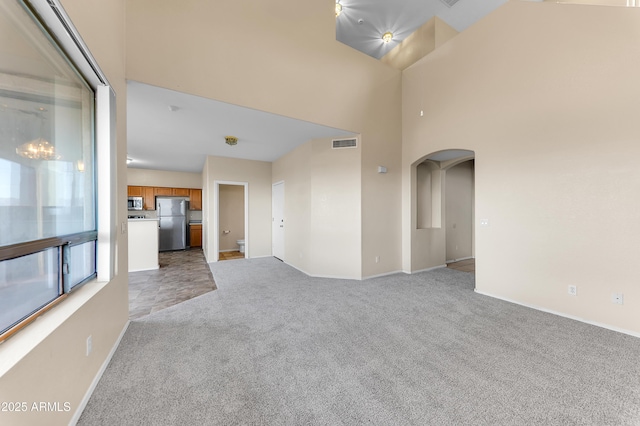 4234 S 62nd Ln, Phoenix, AZ 85043 - empty room featuring visible vents, light carpet, arched walkways, and a towering ceiling