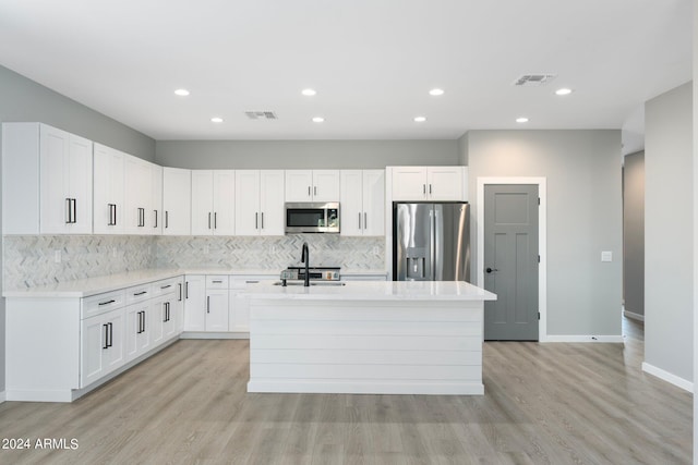 kitchen featuring light wood finished floors, visible vents, appliances with stainless steel finishes, and an island with sink