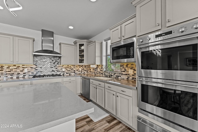 kitchen with tasteful backsplash, wall chimney range hood, stainless steel appliances, and light hardwood / wood-style flooring