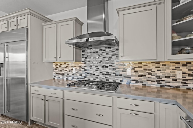 kitchen featuring backsplash, wall chimney exhaust hood, dark hardwood / wood-style floors, and stainless steel appliances