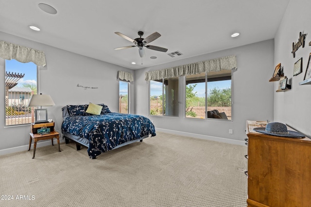 bedroom with multiple windows, ceiling fan, and light colored carpet