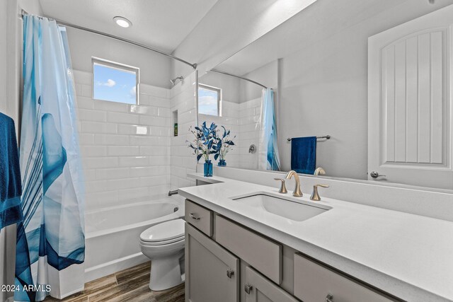 full bathroom with hardwood / wood-style floors, vanity, toilet, and shower / bath combo with shower curtain