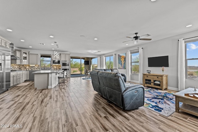 living room with light hardwood / wood-style flooring, ceiling fan, and a healthy amount of sunlight