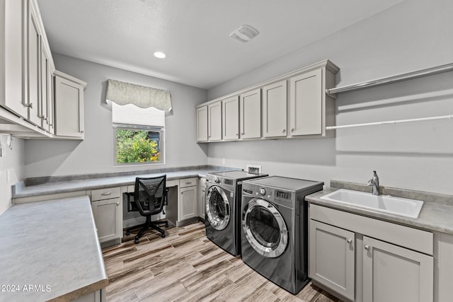 laundry area with cabinets, light hardwood / wood-style flooring, washer and dryer, and sink