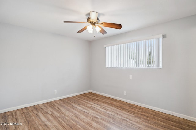 spare room featuring a ceiling fan, baseboards, and wood finished floors