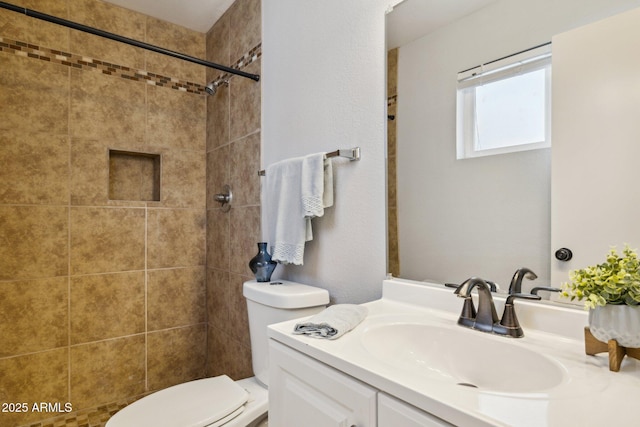 bathroom with toilet, vanity, and a tile shower