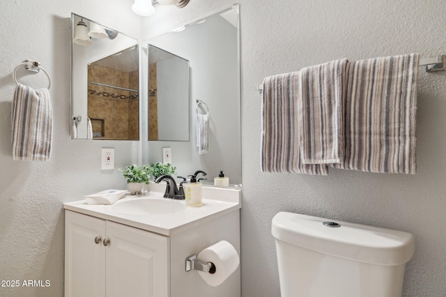 bathroom featuring toilet, vanity, and a textured wall