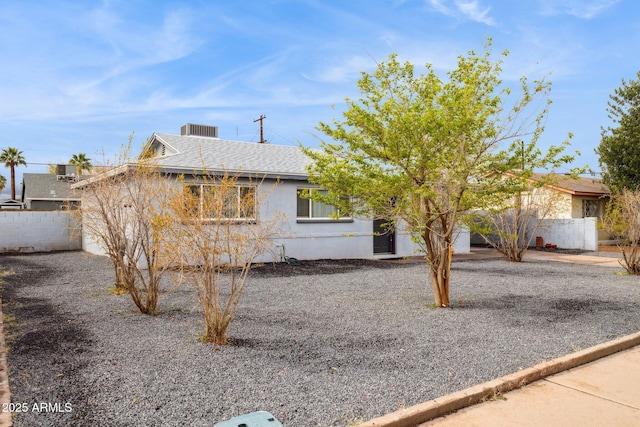 ranch-style house with stucco siding, roof with shingles, and fence