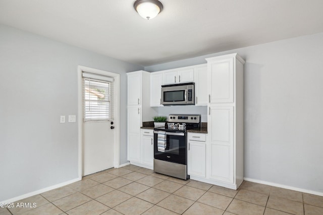 kitchen featuring dark countertops, white cabinetry, stainless steel appliances, and light tile patterned flooring