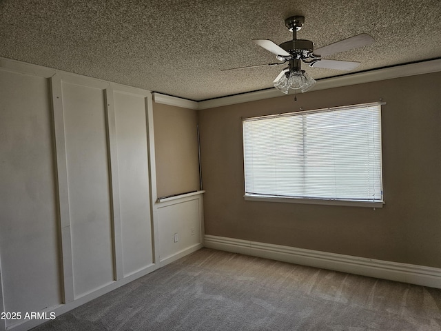 carpeted empty room with ceiling fan and ornamental molding