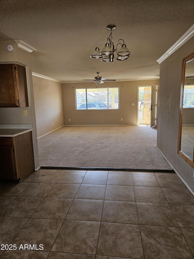 unfurnished dining area featuring ceiling fan with notable chandelier, a healthy amount of sunlight, ornamental molding, and dark carpet