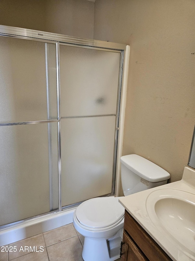 bathroom featuring tile patterned floors, toilet, vanity, and walk in shower