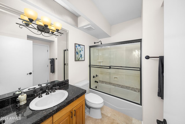 full bathroom featuring tile flooring, an inviting chandelier, enclosed tub / shower combo, vanity with extensive cabinet space, and toilet