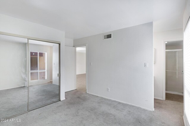 unfurnished bedroom with light colored carpet and a closet